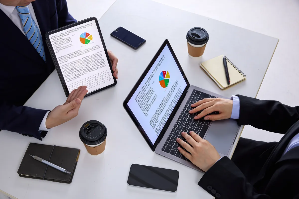 Colleagues reviewing data on a tablet and laptop at a table